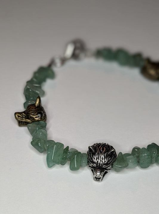 A bracelet made of green aventurine chip beads and metal wolf head shaped bead accents.